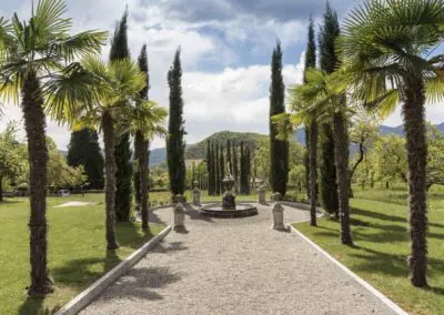 Palm tree-lined garden path with central fountain at Casa Dei Padri retreat center in Italy