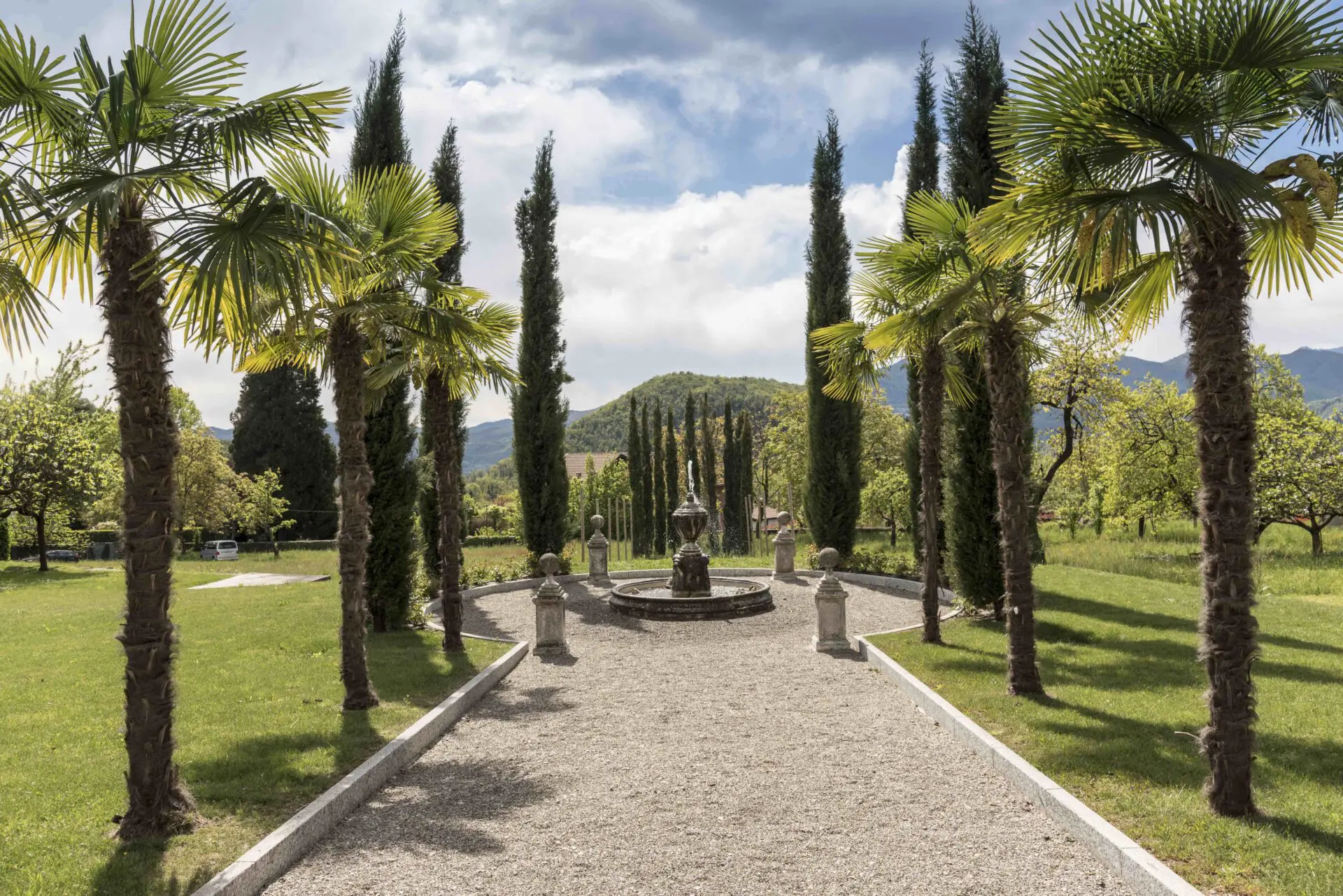 Palm tree-lined garden path with central fountain at Casa Dei Padri retreat center in Italy