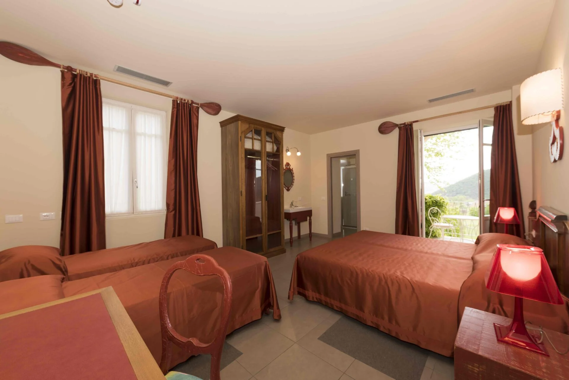 Warm triple guest room with private balcony and hillside view at Casa Dei Padri retreat cente