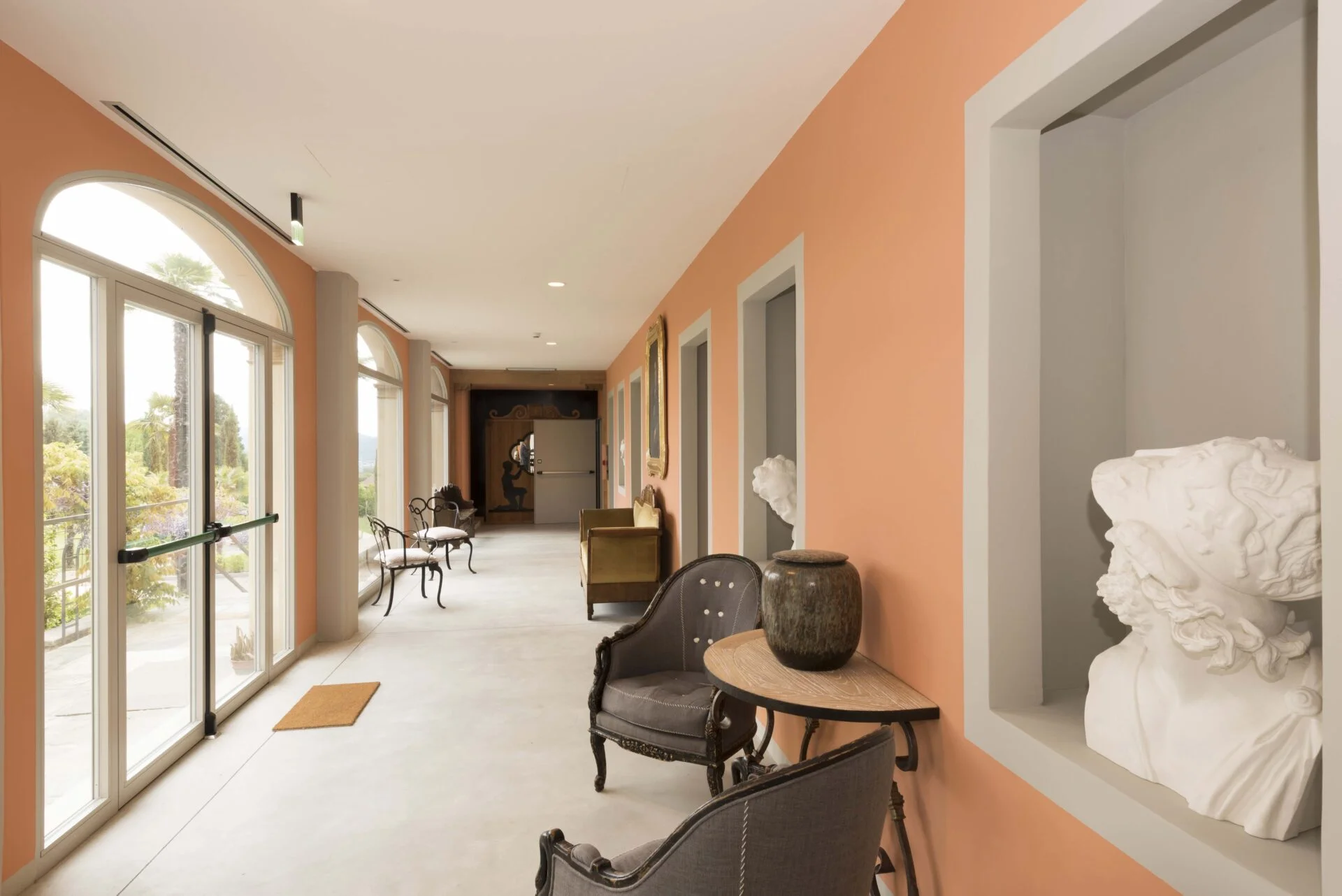 Interior hallway at Casa Dei Padri retreat center with classical sculptures and vintage decor