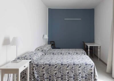 Bright and simple double guest room with twin beds at Casa Dei Padri retreat center