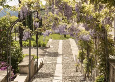 Wisteria-covered archway and stone path at Casa Dei Padri retreat center in Lago d'Orta, Italy