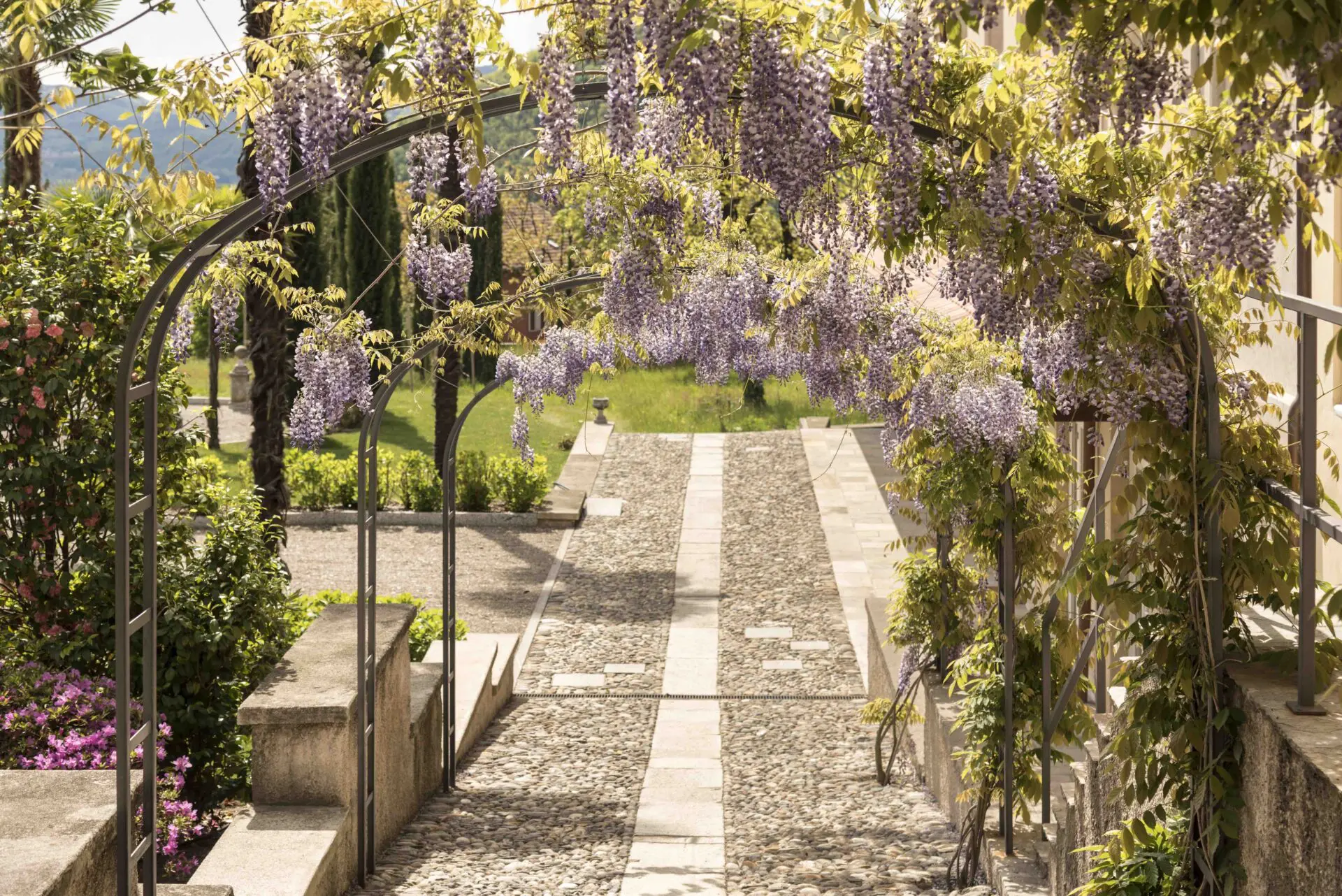 Wisteria-covered archway and stone path at Casa Dei Padri retreat center in Lago d'Orta, Italy