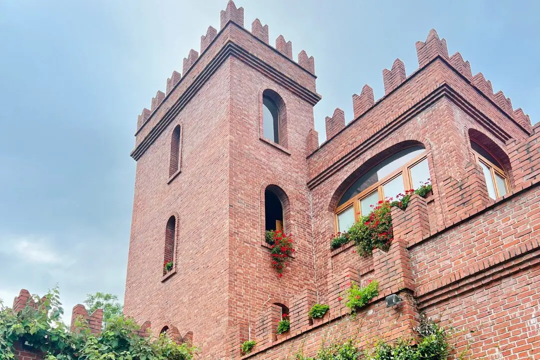 Red brick castle-style vineyard building with flower boxes and arched windows, visited during a private goddess retreat excursion near Lago d’Orta, Ital