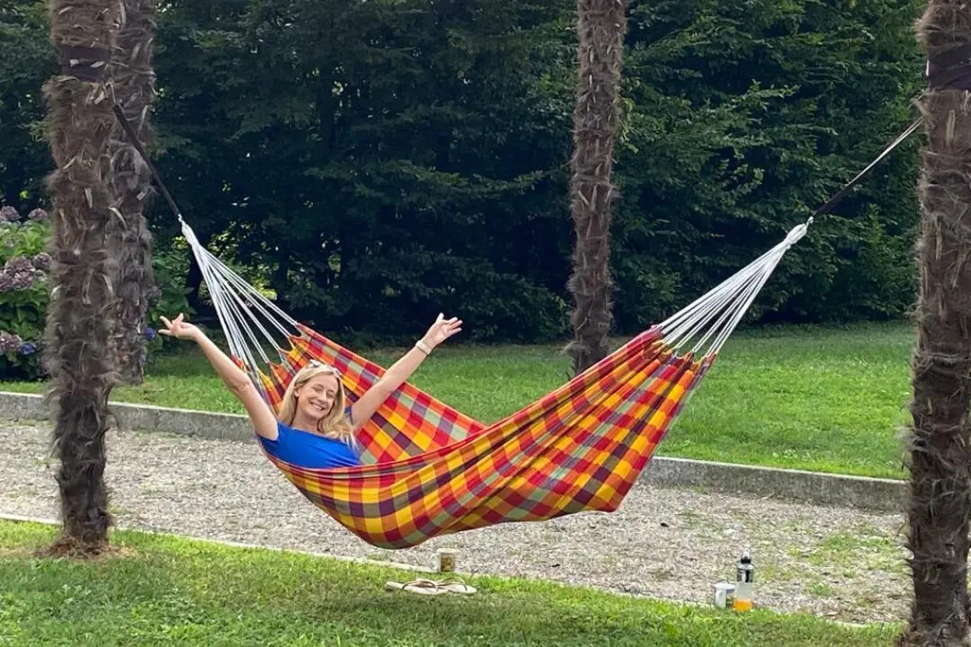 Smiling woman relaxing in a colorful hammock between palm trees at Casa Dei Padri retreat center