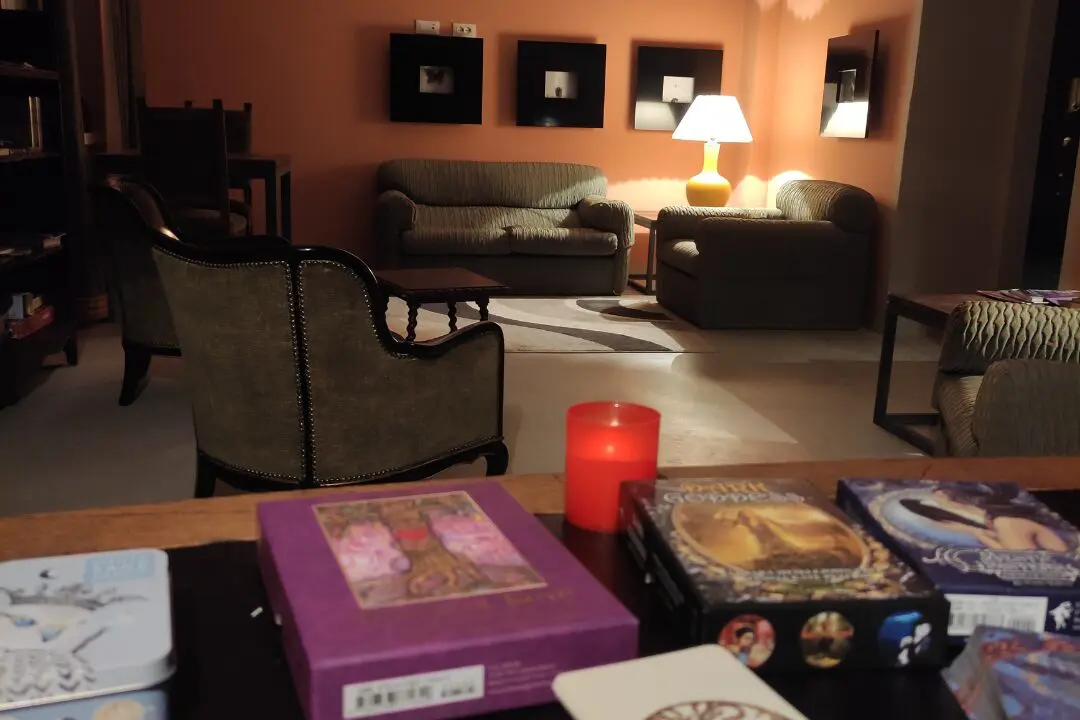 Tarot cards and oracle decks on a wooden table in a cozy retreat library at night