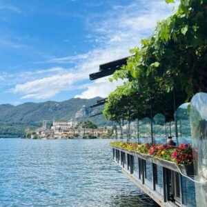 A lakeside restaurant in Orta with lush green vines and colorful flowers overlooking Isola San Giulio